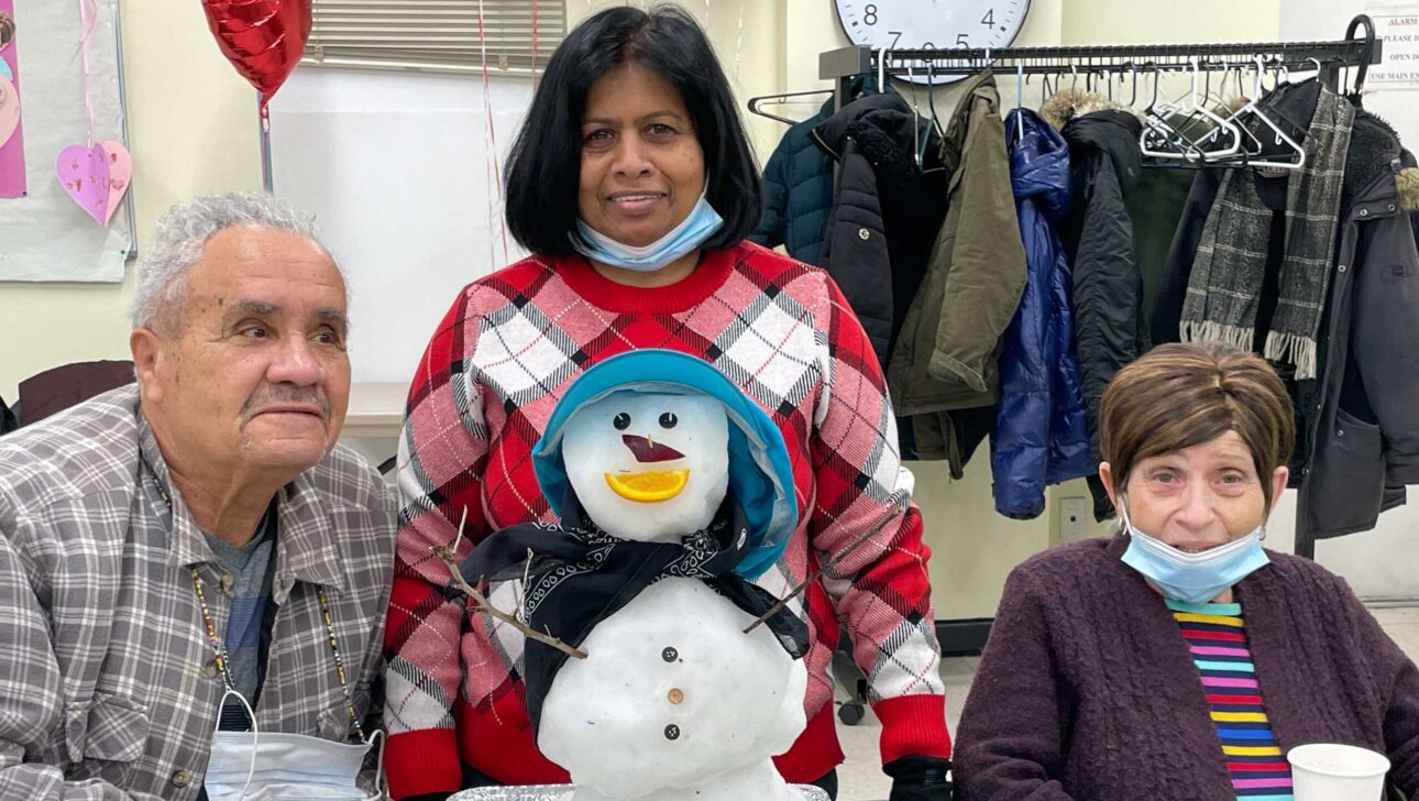 A group of people standing in front of a snowman.