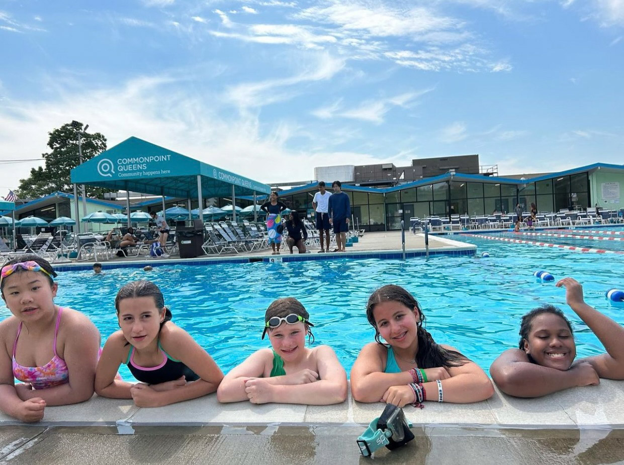 A group of girls posing for a photo in a swimming pool.