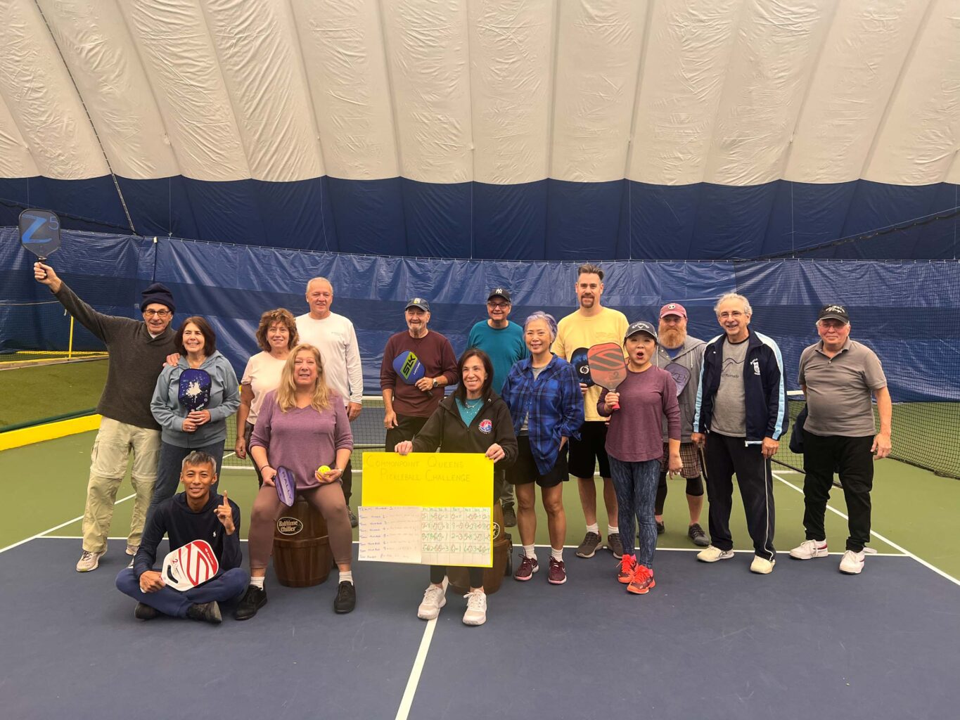 A group of people posing for a picture on a tennis court.