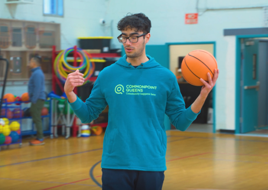 A young man holding a basketball in a gym.