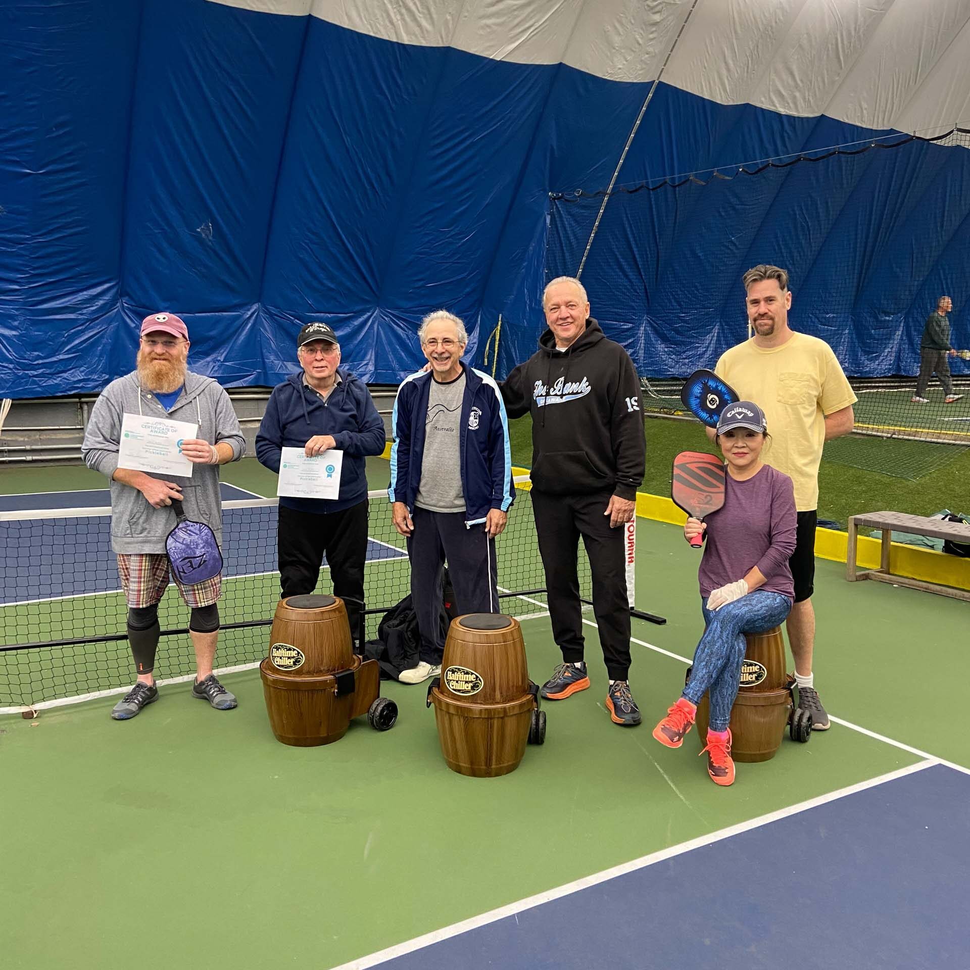 A group of people posing for a picture on a tennis court.