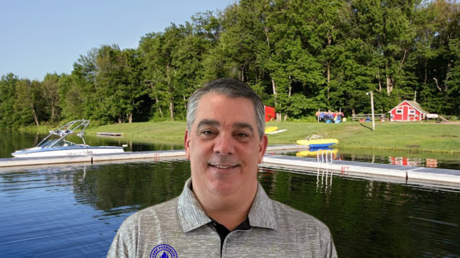 A man in a gray shirt standing in front of a lake, optimizing the SEO for keywords.